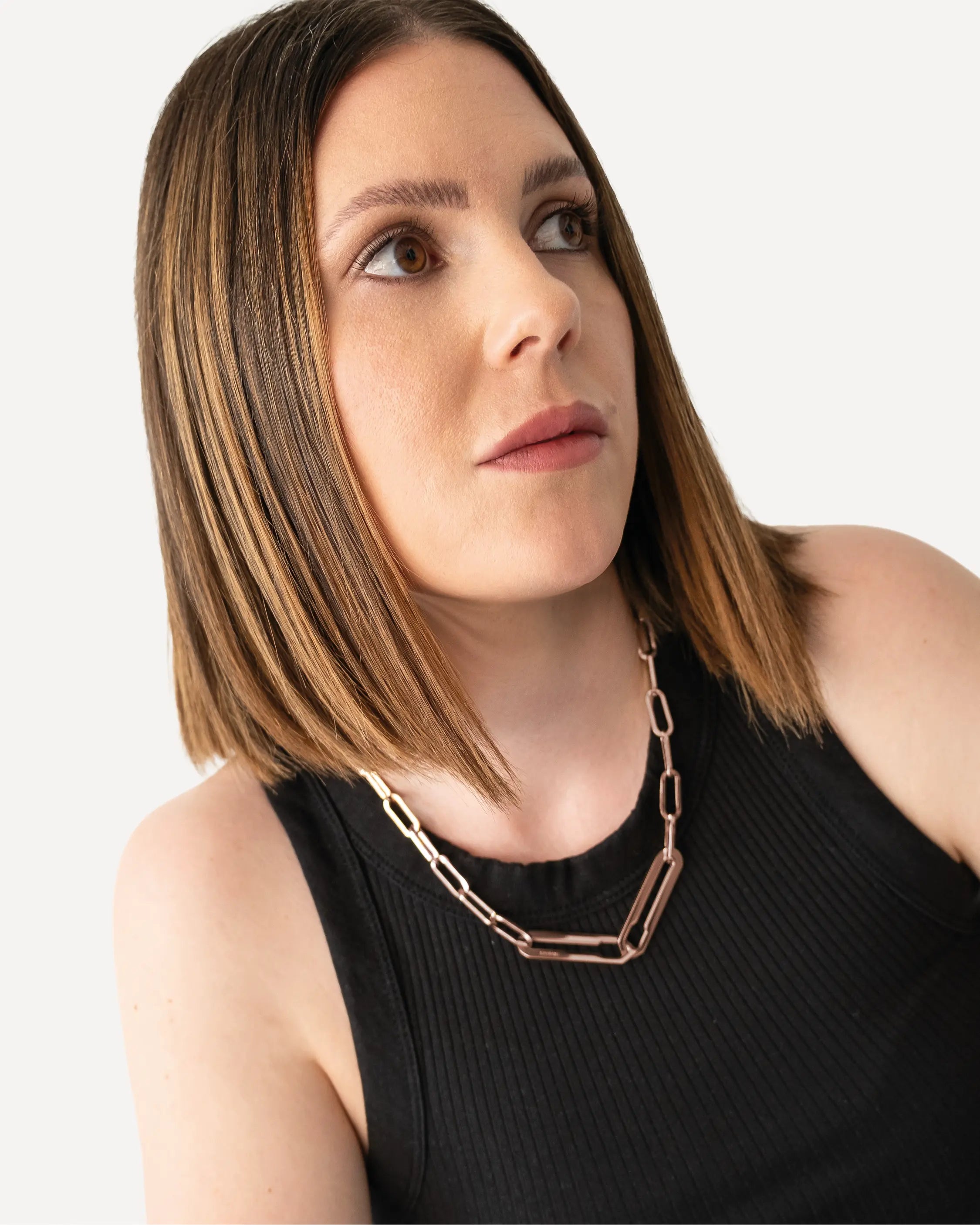 Weibliches Model trägt die Forma Nexus Halskette in Roségold aus 316L-Edelstahl und setzt das elegante Design stilvoll in Szene.