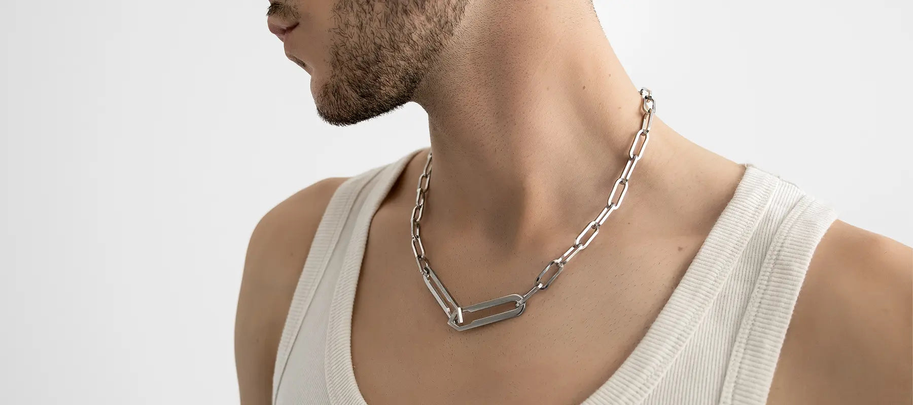 Männliches Model trägt die Forma Infini Halskette in Silber aus 316L-Edelstahl und setzt das elegante Design stilvoll in Szene.