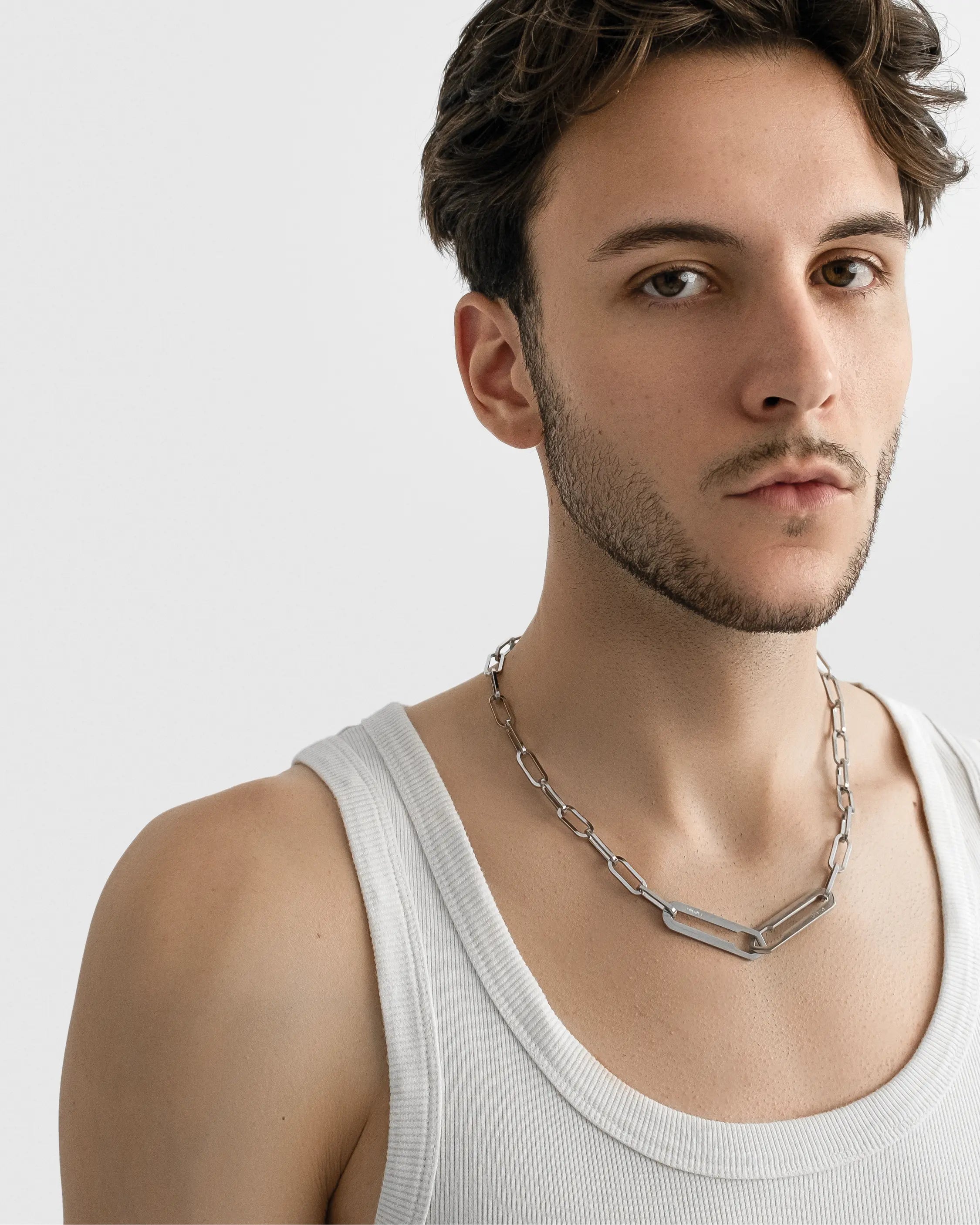 Männliches Model trägt die Forma Infini Halskette in Silber aus 316L-Edelstahl und setzt das elegante Design stilvoll in Szene.